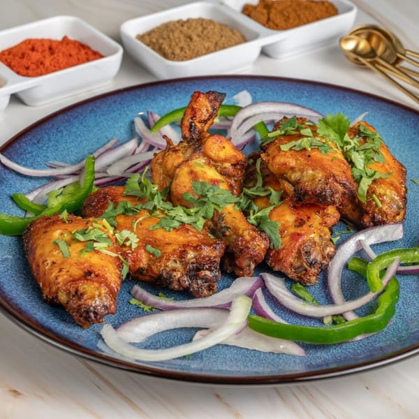 Ashoka Indian Restaurant's chicken wings on a blue plate with onions, peppers, and cilantro.