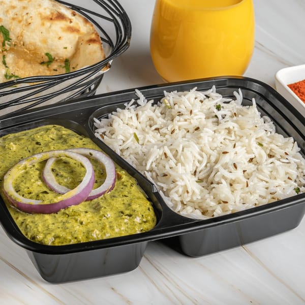 Ashoka Indian Restaurant's Palak Paneer with rice, naan, and a drink on a marble surface.