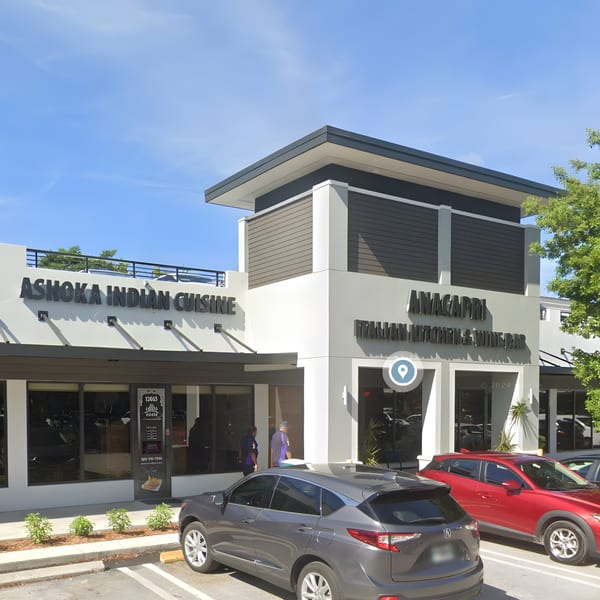 Exterior of Ashoka Indian Cuisine restaurant with a modern facade and parked cars in front.